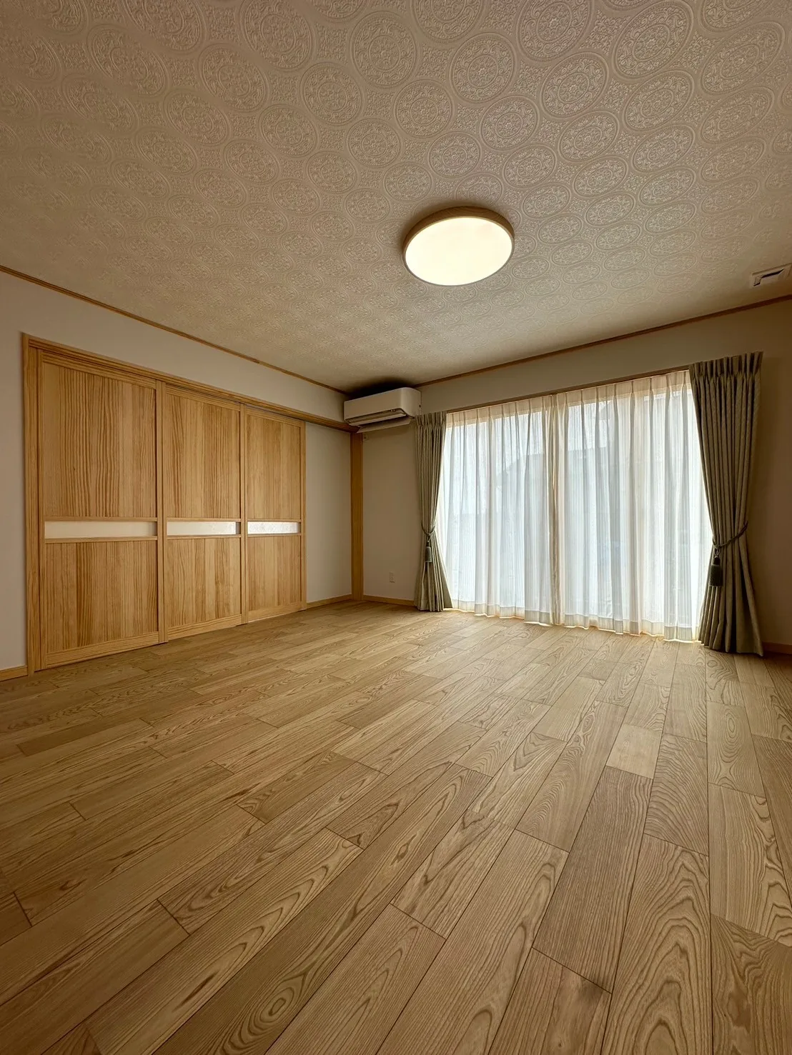 木製建具と大きな掃き出し窓のある、木の床の居室