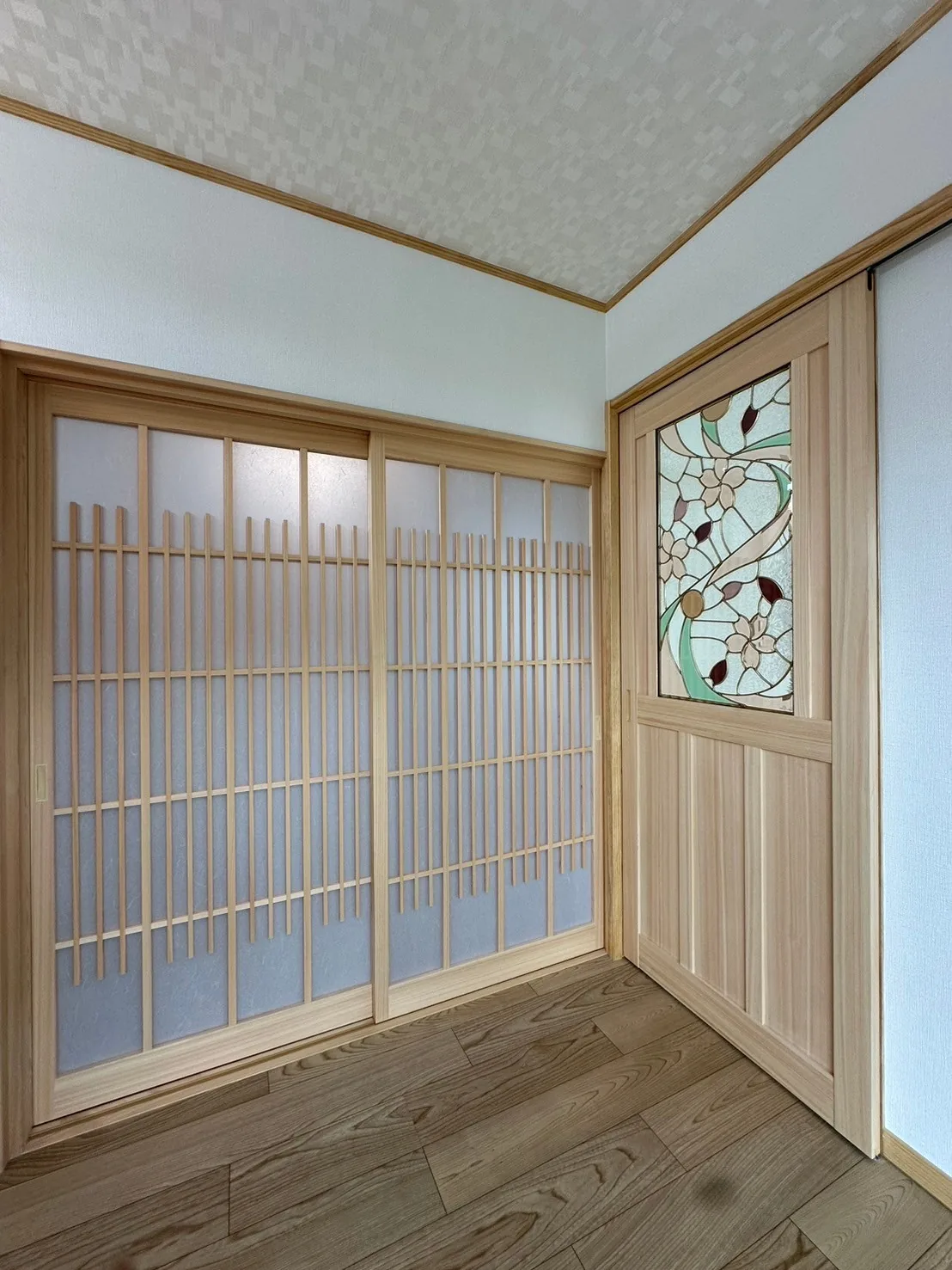木製の格子引き戸とステンドグラス入り建具が並ぶ室内