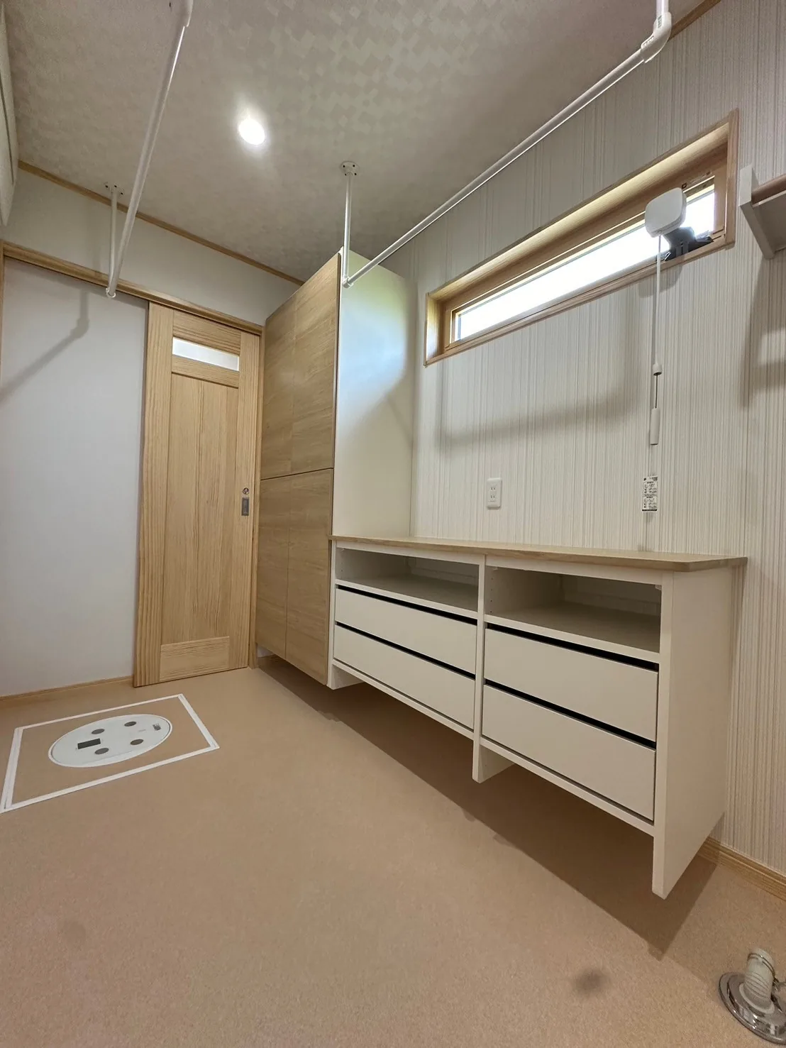 室内物干しと収納棚、横長窓を備えた洗濯室
