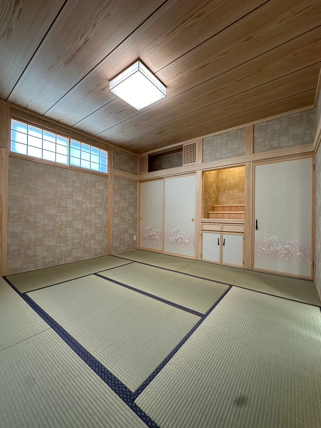 板張り天井と床の間、花柄の襖を備えた畳敷きの和室